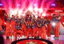 Dynamic digital illustration for CricIndeed IPL 2026 review, featuring a stylized young Indian cricketer lifting a T20 championship trophy against a packed, vibrant stadium background.